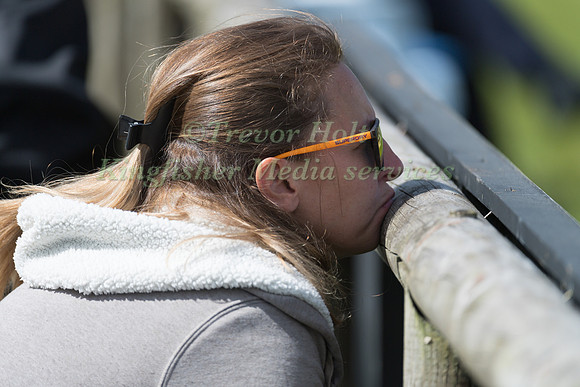 A Spectator rests her chin on the fence whilst watching the dressage competition